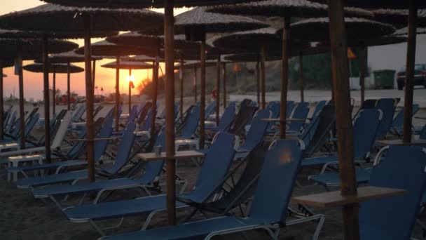 Gün batımı sahne Beach hasır şemsiyeler ve boş şezlong şezlong — Stok video