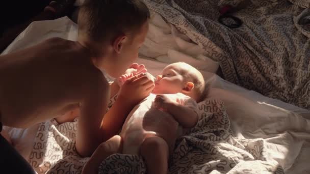 Хлопчик з дитиною вдома. Він любить маленьку сестру і цілує її на щоці — стокове відео