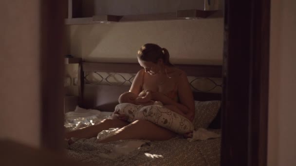 Frau stillt Baby im Schlafzimmer mit schummrigem Licht
