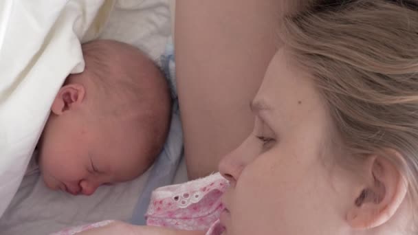 Втомилася і сонна мати дивиться новонароджену дитину — стокове відео