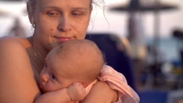 Madre melancólica con bebé en la playa al atardecer — Vídeos de Stock