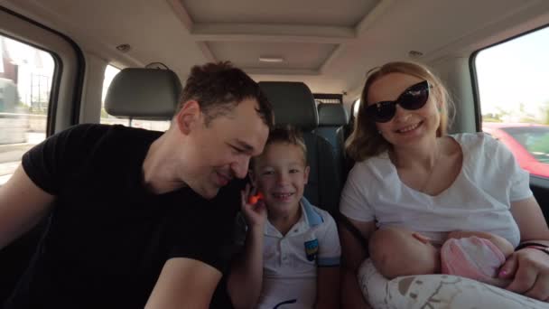 Gelukkige ouders met oudste zoon en dochter van de baby met auto op reis gaat — Stockvideo