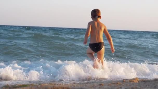 Kind genießt Urlaub an der Küste und rennt zum Schwimmen ins Meer — Stockvideo