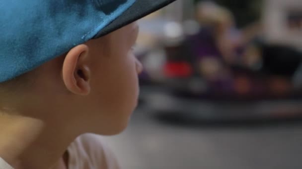 Barnet tittar på stötfångarens bilar i nöjesparken — Stockvideo
