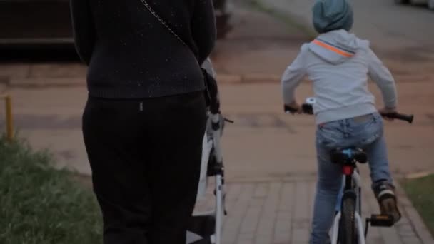 Mutter mit zwei Kindern auf der Straße. Älterer Junge auf dem Fahrrad — Stockvideo