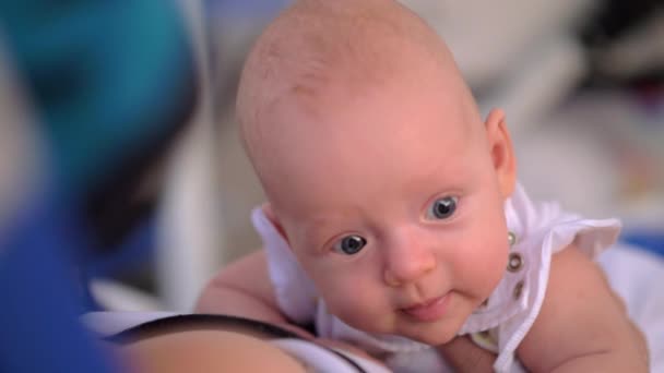 Младенец поднимает голову и смотрит большими голубыми глазами — стоковое видео
