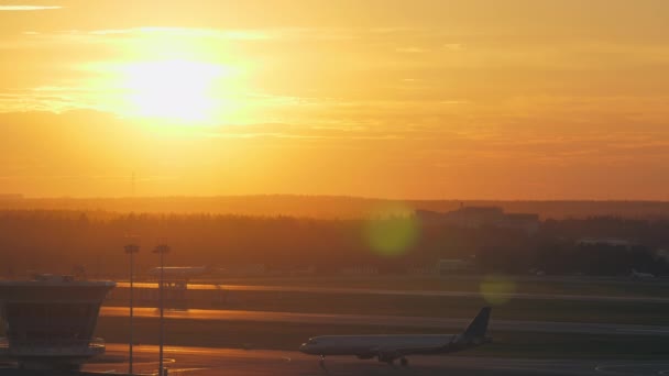 Vista al aeropuerto con avión en movimiento al atardecer dorado — Vídeo de stock