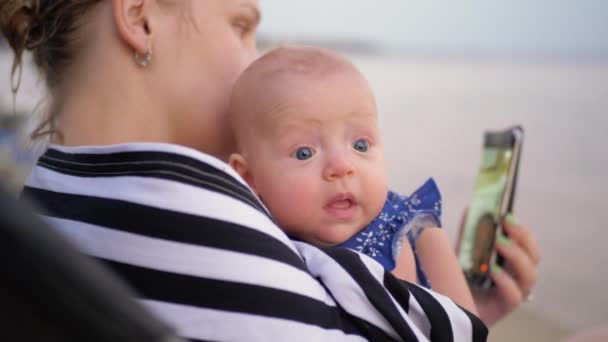 Mãe com bebê vídeo conversando no celular na praia — Vídeo de Stock