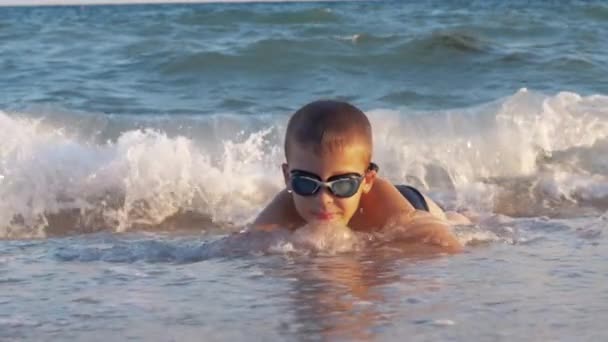 Junge entspannt sich und liegt im flachen Meerwasser — Stockvideo