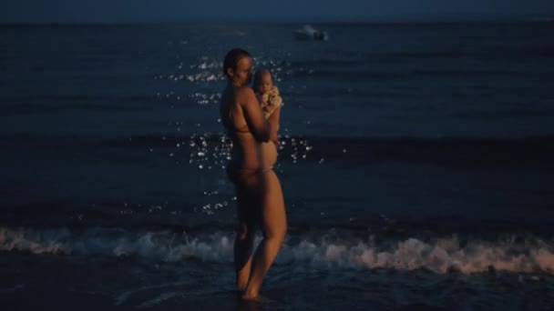 母亲与婴孩在晚上享受海风 — 图库视频影像