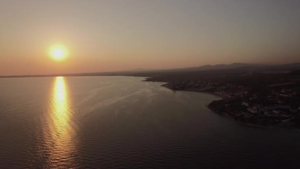 Θέα στη θάλασσα και την παραλιακή πόλη στο ηλιοβασίλεμα, εναέρια. Μακρινή θέα Trikorfo Beach, Ελλάδα — Αρχείο Βίντεο