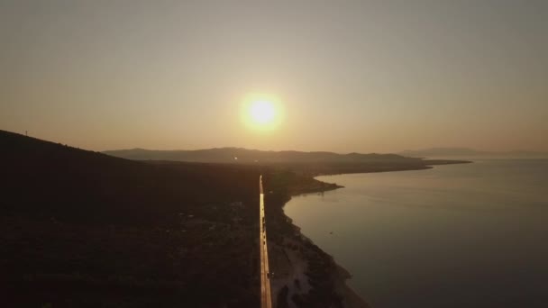 Πετώντας πάνω από την ακτογραμμή και την προκυμαία δρόμο Trikorfo Beach το ηλιοβασίλεμα, Ελλάδα — Αρχείο Βίντεο