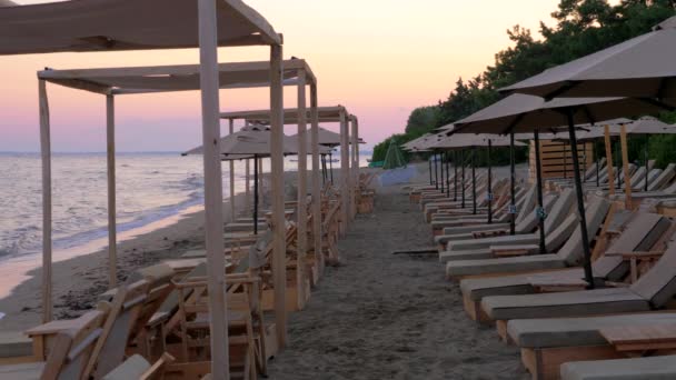 Tenger és a strand, üres napozóágyak naplementekor — Stock videók