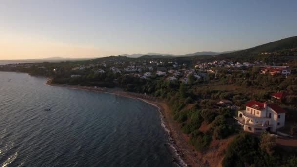 Вид с воздуха на море и берег с курортным городом на закате, Греция — стоковое видео