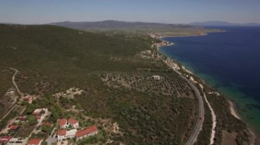 Evler ve yeşil tepeleri ile deniz kıyısı. Trikorfo Beach, Yunanistan'ın havadan görünümü