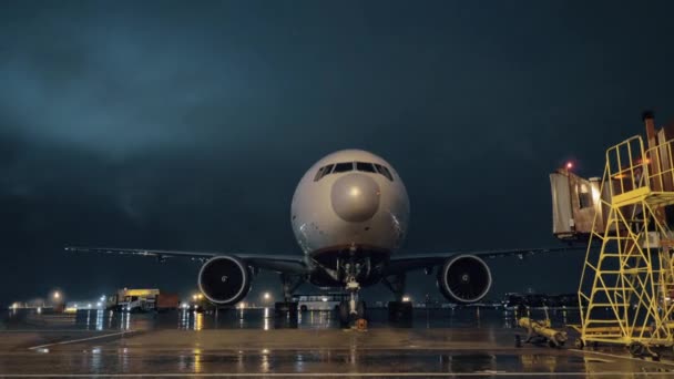 Vista sulla cabina di pilotaggio e sui motori dell'aereo di linea parcheggiato in aeroporto di notte — Video Stock