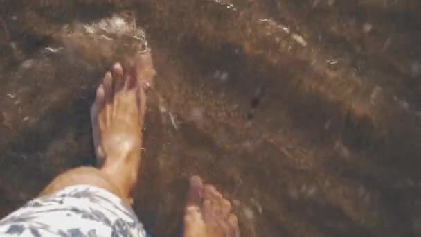 Отдыхающий идет вдоль морского побережья и волны умывают его ноги — стоковое видео