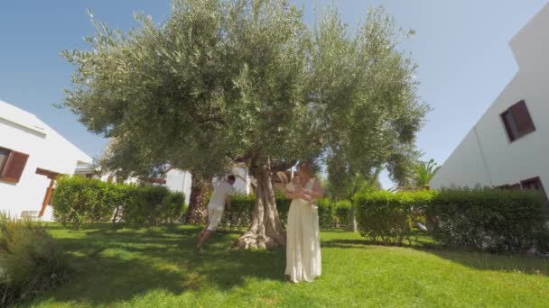 Szczęśliwych rodziców i dzieci w zielonym ogrodzie z duże drzewo oliwne — Wideo stockowe