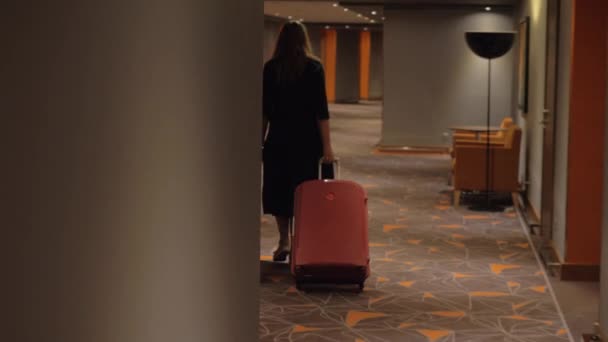 Mujer con maleta caminando a la habitación en el pasillo del hotel — Vídeos de Stock