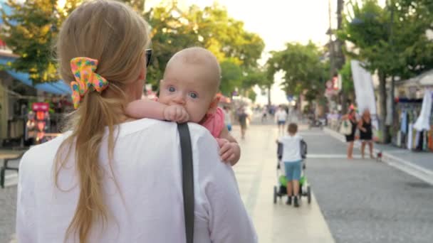 Young mother with baby daughter strolling in the city street — Stock Video