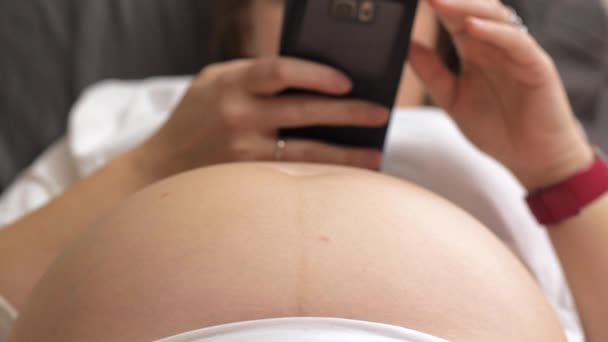 Gravid kvinna med cell, baby sparkar i magen — Stockvideo