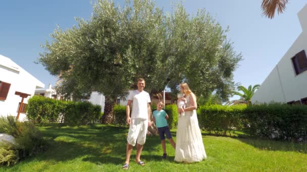 Молодая семья с двумя детьми возле оливкового дерева в саду — стоковое видео