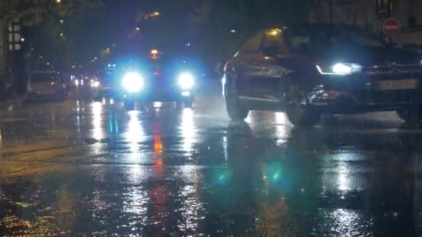 Автомобили с яркими фарами луч вождения в городе в дождливую ночь. Париж, Франция — стоковое видео