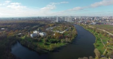 Güneşli şehir manzarasına karşı yeşil ağaçların arasında güzel bir göletin havadan görünüşü