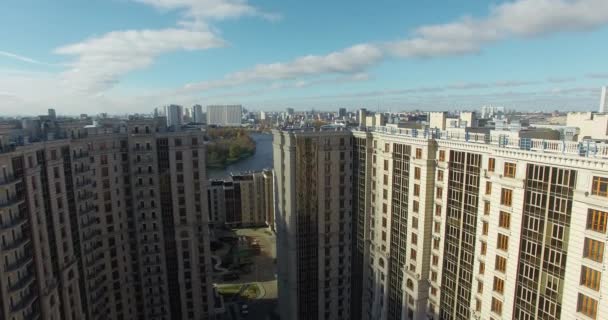 Een luchtfoto van een groot modern woongebouw en een zonnig stadsgezicht erachter — Stockvideo