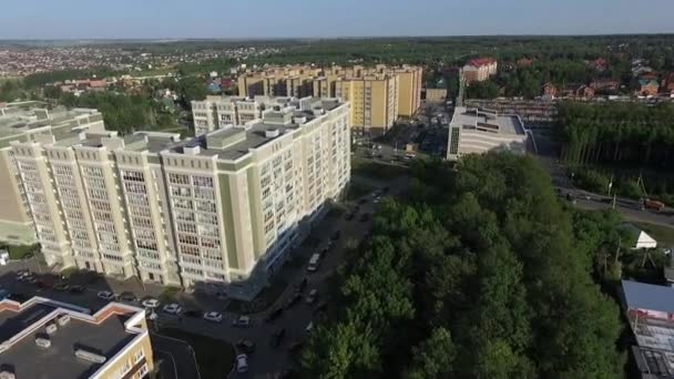 An aerial view of multi storey buildings next to the green forest against blue sky — Stock Video