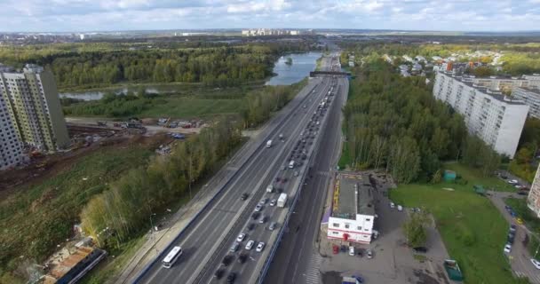 Widok z lotu ptaka niekończącej się autostrady z ruchliwym ruchem w środku zielonej miejskiej scenerii — Wideo stockowe
