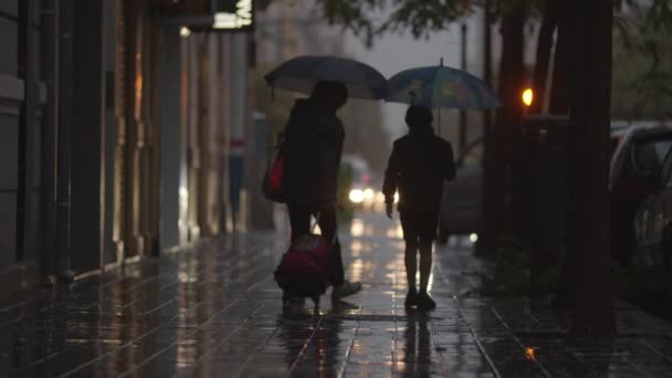 Mamá e hijo caminando en la calle bajo la lluvia — Vídeo de stock