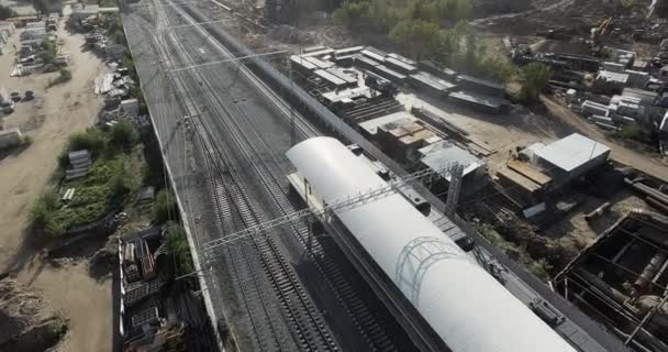 Suburban train departing from the station in industrial city area, aerial — Stock Video