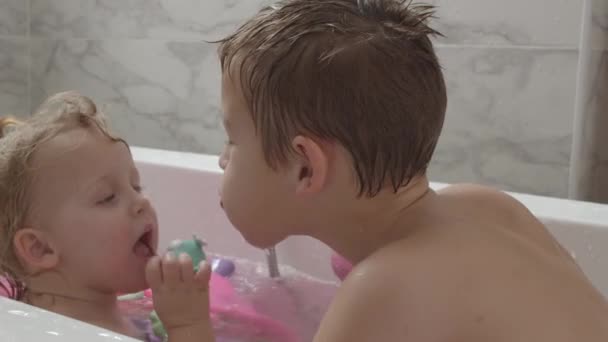 Una bambina e suo fratello giocano nella vasca da bagno — Video Stock