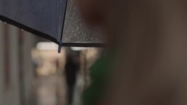 Женщина ходит под зонтиком в дождливом городе — стоковое видео