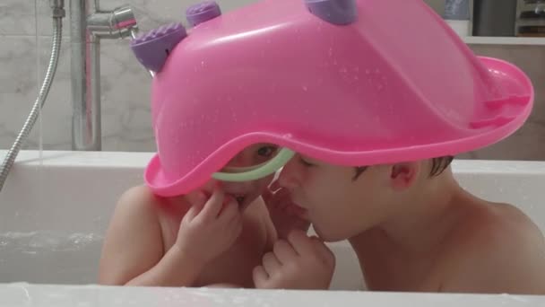 Kinderen baden en hebben plezier. Ze willen onopgemerkt blijven onder het speelgoedbad. — Stockvideo