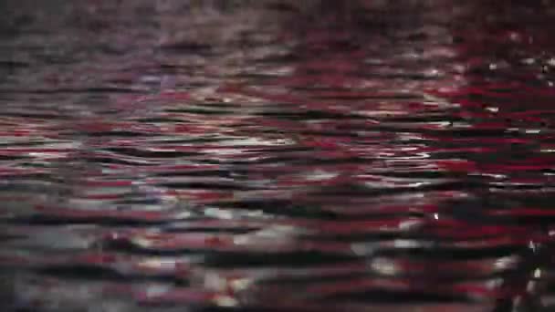 Superficie dell'acqua increspata con riflesso di luce rossa — Video Stock