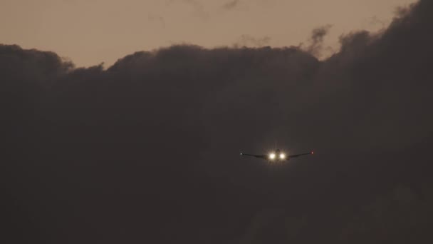 Plane with headlights ascending against heavy clouds in evening sky — Stockvideo