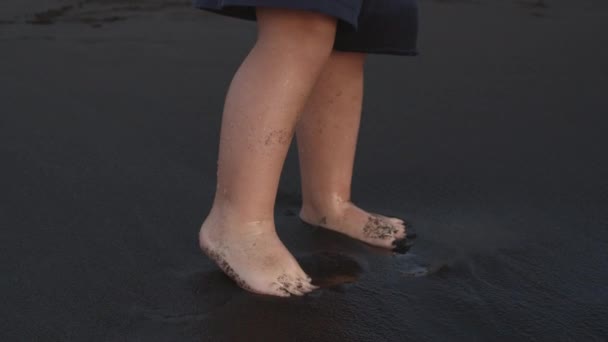 Маленький ребенок на черном песке — стоковое видео