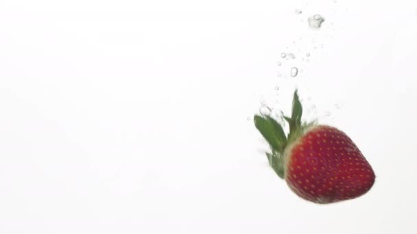 Μια αργή κίνηση μιας φράουλας που πέφτει σε καθαρό νερό — Αρχείο Βίντεο