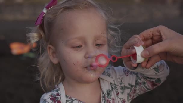 A slowmotion of an adorable little girl who is blowing soap bubbles — Stock Video