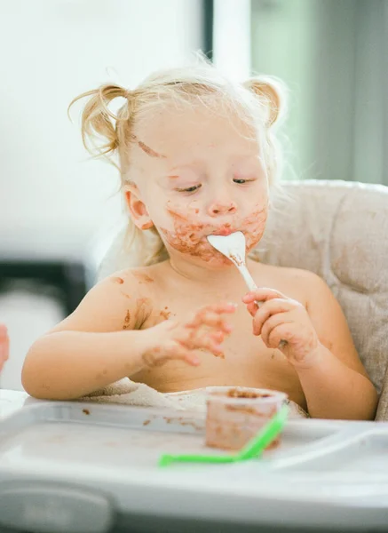 Baby with dirty face enjoying her meal — Stock Photo, Image