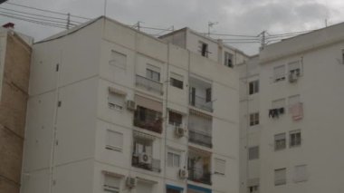 Pencerelerinde panjurlar olan beyaz cephe dairesi.