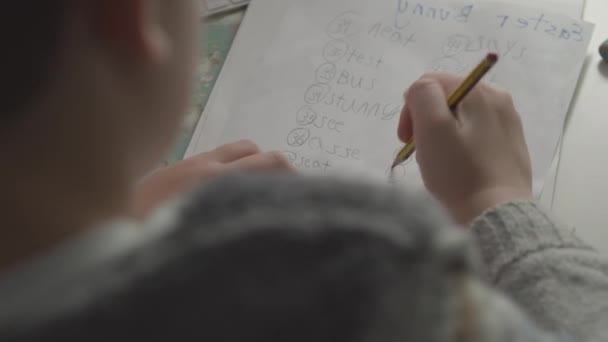 Ребенок, изучающий английский и составляющий список слов — стоковое видео