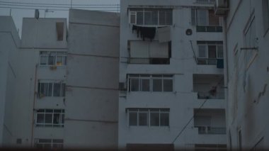 Pencereleri panjurlu apartman bloğu, akşam manzaralı.