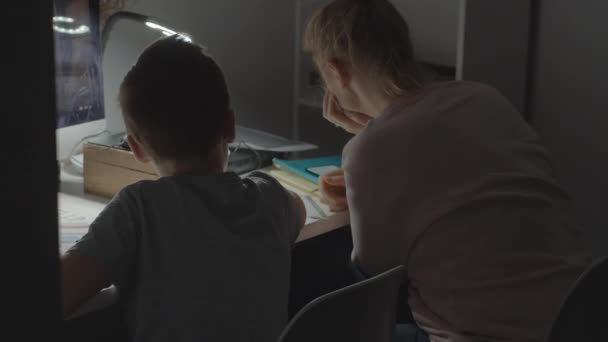 Мама помогает сыну с учебой во время карантина Ковид-19 — стоковое видео