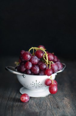 ahşap arka plan üzerinde bir kevgir içinde olgunlaşmış üzümler