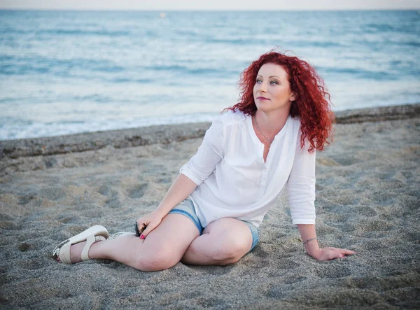 Jolie fille rousse assise sur le sable — Photo