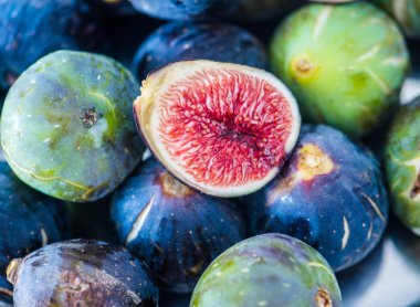 Bütün ve dilimlenmiş incir bir tabak ve ahşap bir masa. Güzel natürmort.