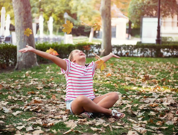 Podzimní den veselá dívka vyvolá žluté listy — Stock fotografie